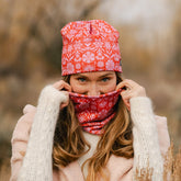 Person wearing a red floral hat and neckwarmer in a natural setting